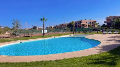 a swimming pool with blue water in a park at Ben House Palmeraie in Marrakech