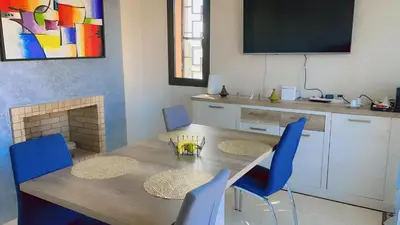 a dining room with a table and chairs and a television at Ben House Palmeraie in Marrakech