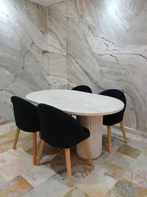 a table and chairs in a room with a marble wall at Cosy appartement Victor Hugo in Marrakech