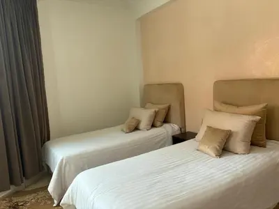 two beds in a room with white sheets at Elegant appartement a Gueliz in Marrakech