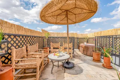 a patio with a table and chairs and an umbrella at Riad privatif 2 Chambres, Jacuzzi Proche des Palais in Marrakech