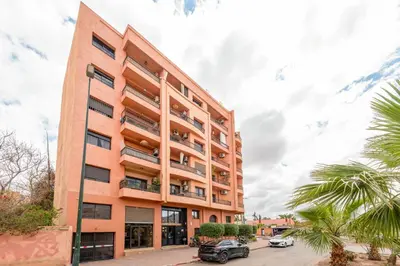 an orange building with cars parked in front of it at Le Darna - Marrakech Victor Hugo - 2prs - Wifi in Marrakech