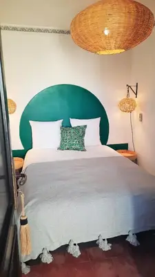 a bedroom with a large bed with a green headboard at RIAD AWEL - 3 chambres & jacuzzi au coeur de la Medina in Marrakech