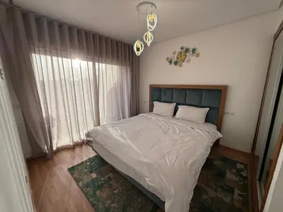 a bedroom with a bed with white sheets and a window at Appartemen luxe in Marrakech