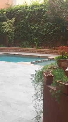 an empty swimming pool in a yard with plants at Cosy et confortable in Marrakech