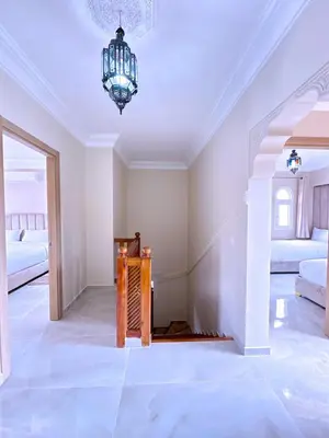 a white room with a chandelier and two beds at New! Duplex Annakhil , Calme et proximité centre in Marrakech