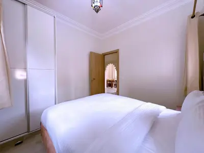 a white bedroom with a bed and a chandelier at New! Duplex Annakhil , Calme et proximité centre in Marrakech