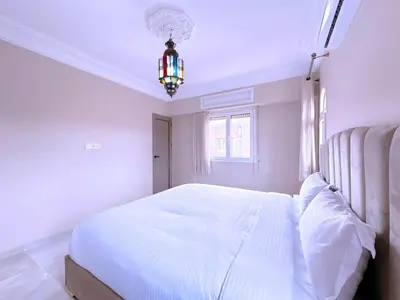 a bedroom with a large white bed with a chandelier at New! Duplex Annakhil , Calme et proximité centre in Marrakech
