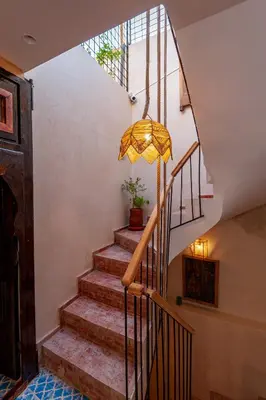 a staircase with a yellow umbrella in a house at Riad Akkioui in Marrakech