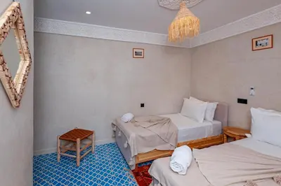 a room with two beds and a chandelier at Riad Akkioui in Marrakech