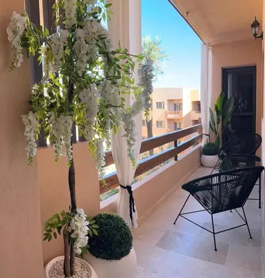 a balcony with flowering trees and a window at Prestige Cocon in Marrakech
