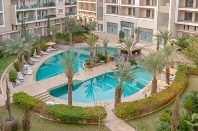 an overhead view of a swimming pool with palm trees and buildings at pearl garden in Marrakech