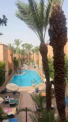 a pool with a palm tree in a resort at Riad Marrakech in Marrakech
