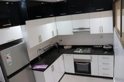 a kitchen with white cabinets and black counter tops at appartement 3 chambres gueliz only families in Marrakech