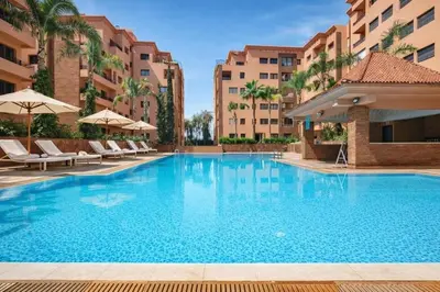 a swimming pool at a hotel with chairs and umbrellas at Appartement avec piscine in Marrakech