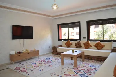 a living room with a couch and a tv at Appartement avec piscine in Marrakech