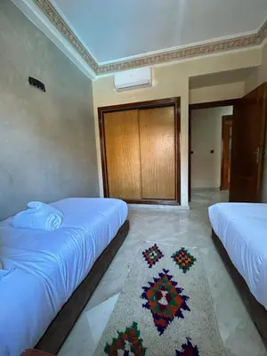 two beds in a room with a rug on the floor at Appartement avec piscine in Marrakech