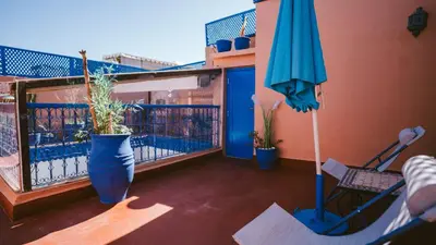 a balcony with an umbrella and a chair and a table at Riad KAN ZAMAN in Marrakech