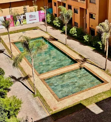 an overhead view of a pool with palm trees and a building at Bonheur partagé 2 in Marrakech