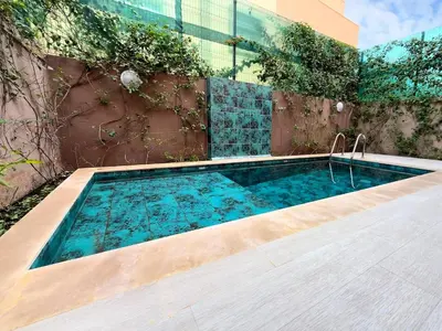 a swimming pool with a wooden floor and a building at Maison de Vacances Targa avec Piscine & Terrasse à Marrakech in Marrakech
