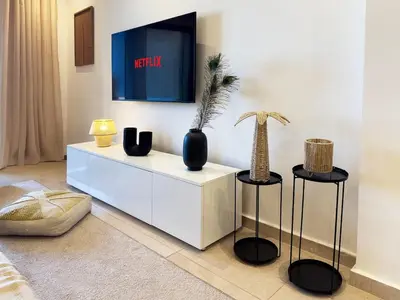 a living room with a white cabinet with two stools at Appartement tout confort à Marrakech avec Piscine et Capacité 4 Personnes in Marrakech