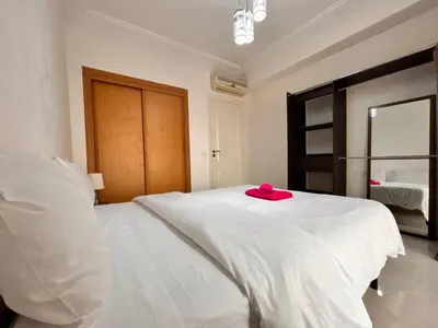 a white bed with a pink hat on top of it at Lumière in Marrakech