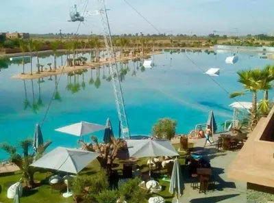 a large pool of blue water with tables and umbrellas at Villa ilyana, Atlas Villa in Marrakech