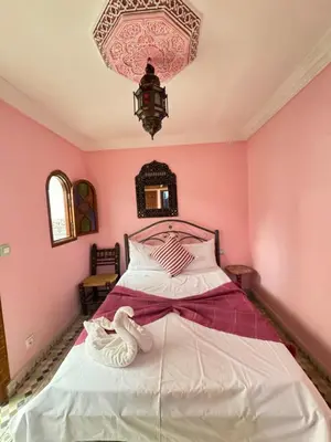 a bedroom with a bed with pink walls and a chandelier at ASA House in Marrakech