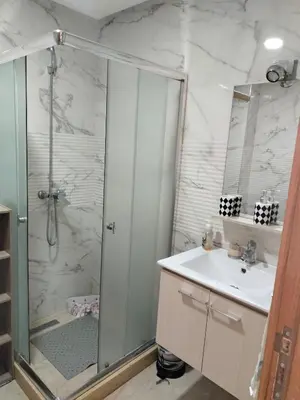 a bathroom with a shower and a sink and a mirror at Appartement Confort & Style à Charaf - Marrakech in Marrakech