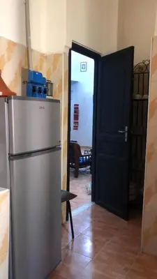 a kitchen with a refrigerator and a black door at Dar DAROUNE in Marrakech