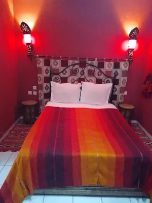 a bedroom with a bed with a colorful blanket on it at Riad avec jardins et piscines in Marrakech