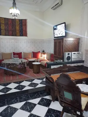 a living room with a couch and a tv at Riad avec jardins et piscines in Marrakech