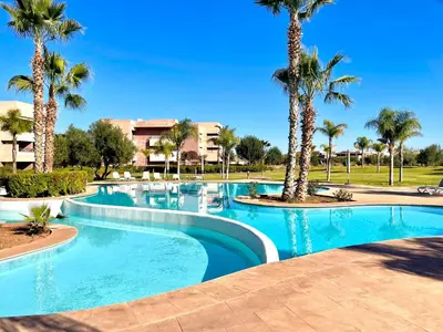 a swimming pool with palm trees in a resort at Prestigia golf in Marrakech