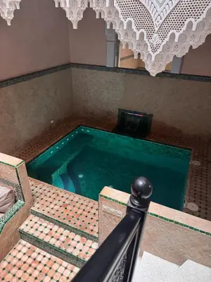 a pool of water in a room with a table at Riad Naïel piscine privée in Marrakech