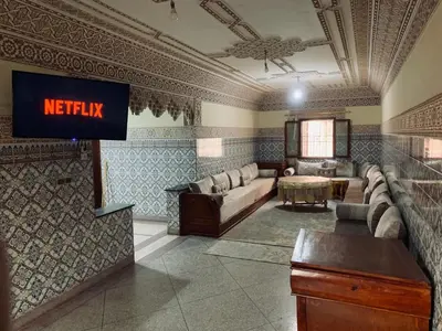 a living room with a couch and a tv on the wall at 120m2, Centre Marrakech, Traditional in Marrakech