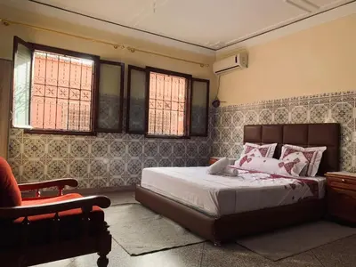 a bedroom with a bed and a chair and windows at 120m2, Centre Marrakech, Traditional in Marrakech