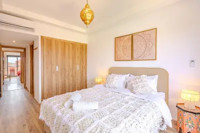a bedroom with a large bed with a white comforter at Évasion à NORIA - Vue Piscine et Charme Local in Marrakech