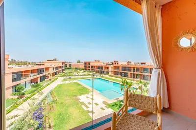 a balcony with a view of a pool and a building at Évasion à NORIA - Vue Piscine et Charme Local in Marrakech