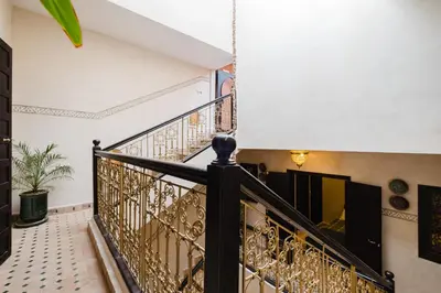 a staircase in a house with a black and gold railing at Riad Emeraude Cozy Riad with Shared Pool 4 Room in Marrakech