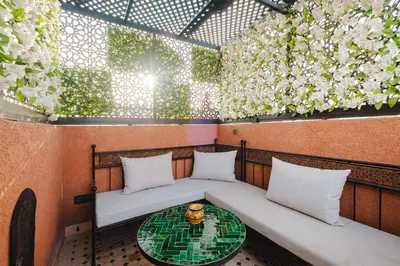 a small balcony with two beds and a table at Riad Emeraude Cozy Riad with Shared Pool 4 Room in Marrakech