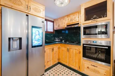 a kitchen with wooden cabinets and a stainless steel refrigerator at Riad Emeraude Cozy Riad with Shared Pool 4 Room in Marrakech