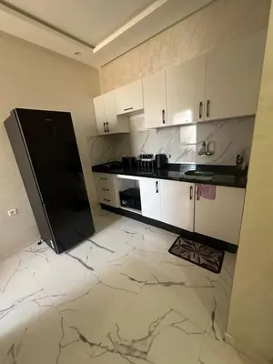 a kitchen with white cabinets and a black refrigerator at Appartement cozy in Marrakech