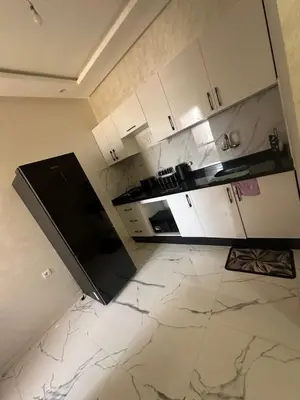 a kitchen with white cabinets and a black appliance at Appartement cozy in Marrakech