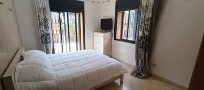 a bedroom with a white bed and two windows at Rez-de-chaussée avec piscine in Marrakech