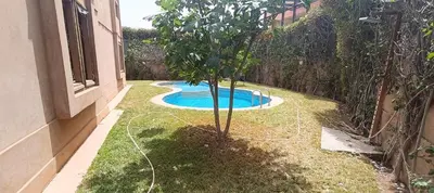 a garden with a tree and a swimming pool at Rez-de-chaussée avec piscine in Marrakech