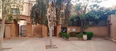 a tree in front of a building with a staircase at Rez-de-chaussée avec piscine in Marrakech