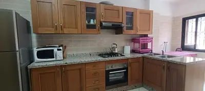 a kitchen with wooden cabinets and a microwave at Rez-de-chaussée avec piscine in Marrakech