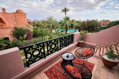a balcony with a table and chairs on a patio at Golden Palms Marrakech in Marrakech