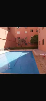 a large blue swimming pool in front of a building at Appartement a marrakech gueliz au centre ville in Marrakech
