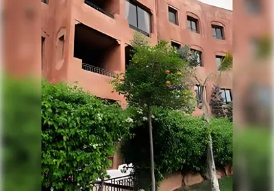 an orange tree in front of a building at Ehden Properties - Appt spacieux dans la prestigieuse River Palm Marrakech in Marrakech